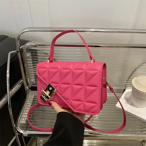 Sac à main matelassé rose vif avec fermoir doré et bandoulière sur présentoir moderne