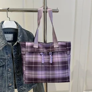Sac fourre-tout à carreaux violets avec breloques tissées accroché sur un cintre