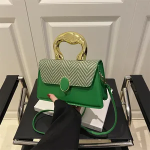Green leather handbag with gold metal handle and woven flap displayed on a chair