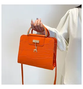 Detail of orange embossed leather handbag with gold deer pendant and round metal handle