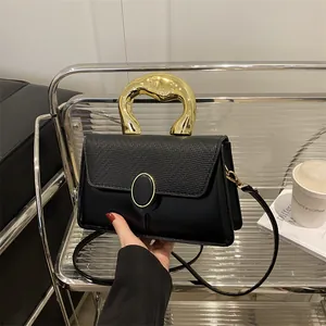 Chic black crossbody bag with unique gold molten handle and embossed flap detail