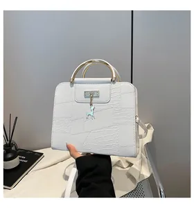 Detail of white textured leather handbag with gold round handle and deer charm