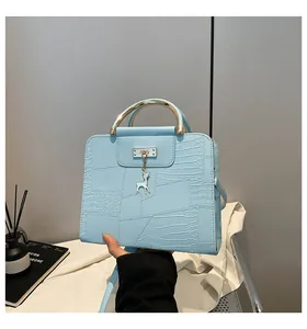 Close-up of light blue crocodile texture handbag with golden handle and deer charm