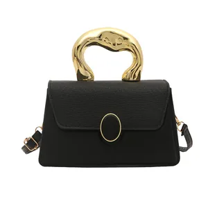 Minimalist black crossbody handbag with artistic gold handle and textured faux leather