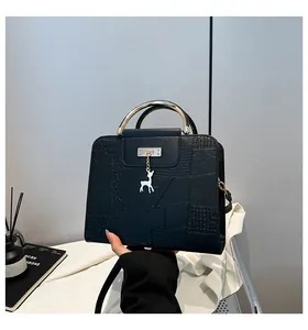 Detail of black faux crocodile leather bag with geometric stitching and silver deer charm