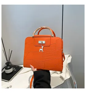 Detail of orange embossed leather crossbody bag with golden handle and deer charm