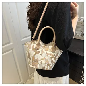Detailed view of beige tote bag with light brown and white floral embroidery pattern