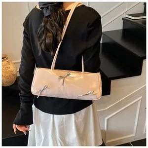 Detail of pink shoulder bag with shiny PU finish and silver bow accents on model