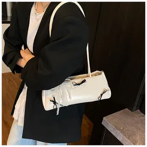 Detail of white shoulder bag with black bows, lace trim and pearl accents