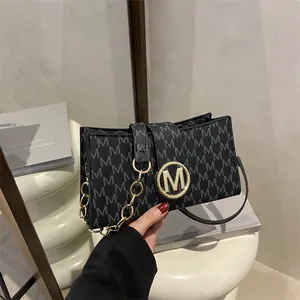 Chic black monogram flap bag with golden M logo and chain strap on a minimalist background