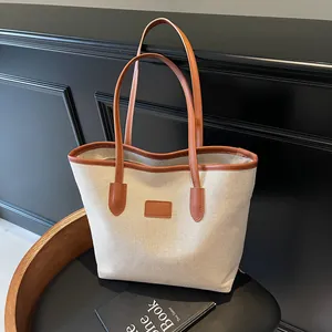 Minimalist canvas tote bag with brown leather trim and large capacity for commuting