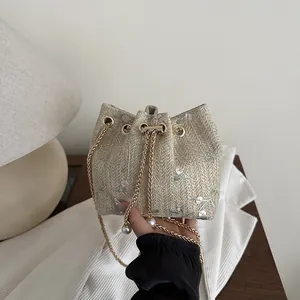 Beige woven bucket bag with floral embroidery, pearl charms and gold chain strap