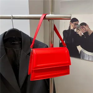 Bright red glossy leather crossbody bag with embossed square design and shoulder strap