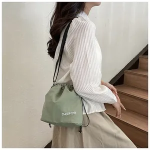 Detailed view of sage green nylon drawstring bucket bag featuring white fashion print logo