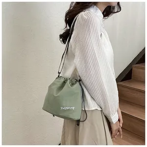 Detail of green nylon drawstring bucket bag with fashion print and black strap