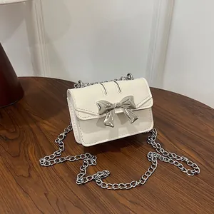 Elegant off-white mini crossbody bag with silver metal bow and slim chain strap