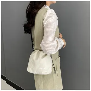 Detail of a white drawstring bucket bag with FASHION print and thin black shoulder strap