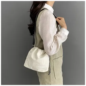 Detail view of cream nylon drawstring bucket bag with black strap and fashion embroidery