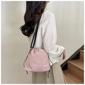 Detailed view of pink nylon bucket bag featuring a drawstring and FASHION lettering