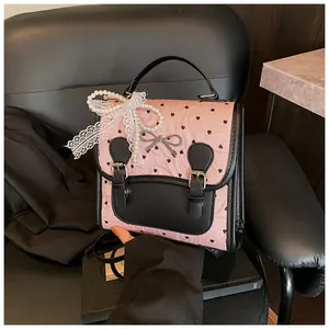 Detail der rosa Tasche mit Herzmuster, Perlengriff und Schleife aus Spitze