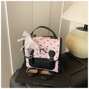 Detailansicht der rosa Handtasche mit Herzstruktur, Perlenanhängern und Spitzenschleife