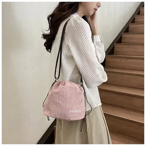 Close-up of pink nylon bucket bag featuring drawstring closure and white fashion lettering