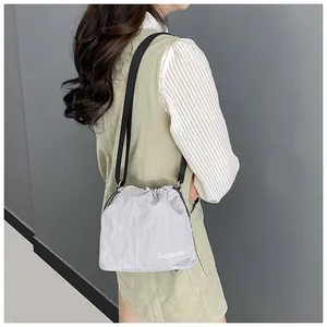 Detailed view of light gray nylon drawstring bucket bag with FASHION lettering