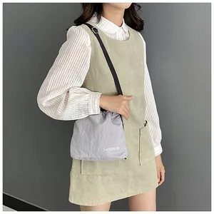 Detail of grey drawstring nylon crossbody bag with white FASHION lettering text