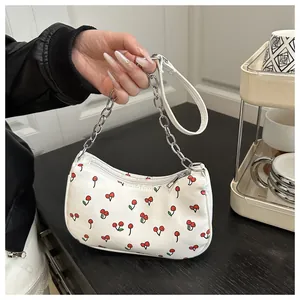 Detail view of white PU underarm bag with red cherry prints and silver chain strap
