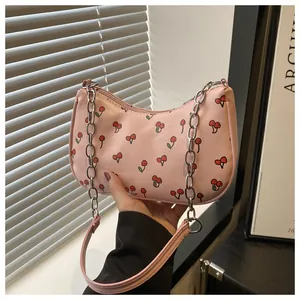 Close-up of pink underarm bag with cherry print and silver chain strap detail