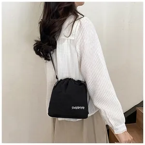 Detail of black drawstring nylon bucket bag with fashion print worn crossbody