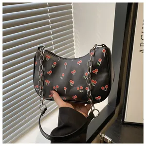 Detail of black cherry print hobo bag featuring silver chain and leather shoulder strap