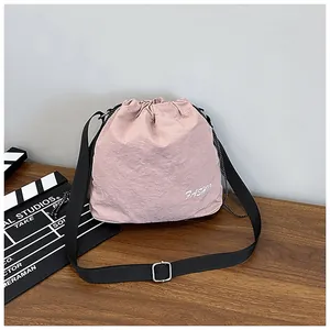 Macro detail of drawstring closure and textured nylon fabric on the pink bucket bag