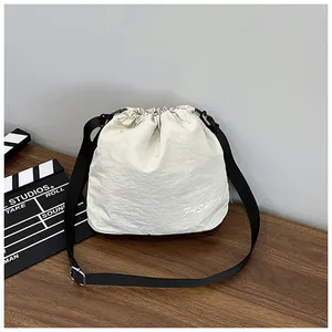 Detail of off-white drawstring bucket bag with black strap and fashion embroidery