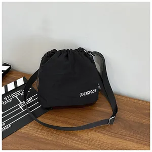 Detail view of black drawstring bucket bag with white fashion text on wooden surface