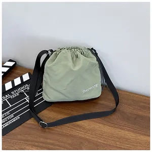 Detail of olive green nylon drawstring bucket bag featuring white fashion print and black strap