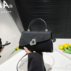Glossy black crossbody bag with silver glitter flap and heart buckle in a scenic setting