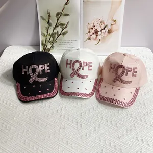 Close-up of three baseball caps with pink rhinestone HOPE letters and ribbon designs