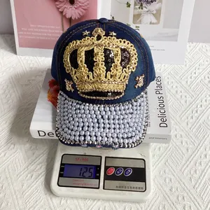 Detail of denim crown baseball cap with pearls, rhinestones and golden rope on a scale