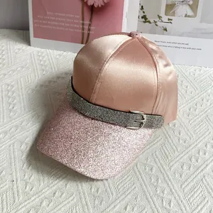 Detail of pink satin baseball cap with glitter brim and rhinestone belt buckle accent