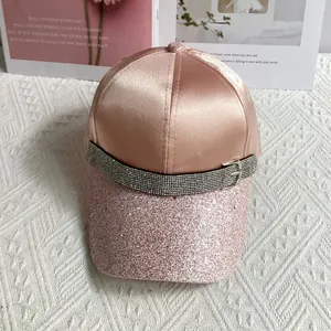 Macro detail of pink satin baseball cap featuring glitter visor and rhinestone belt buckle
