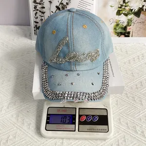 Dettaglio cappello di jeans blu con strass Love che pesa 103g su una bilancia digitale