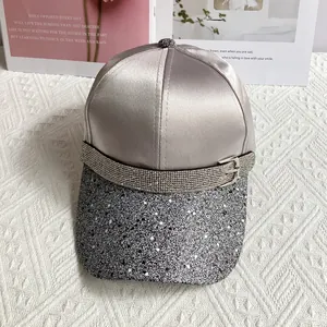 Detail of satin baseball cap featuring shimmering glitter brim and rhinestone belt buckle