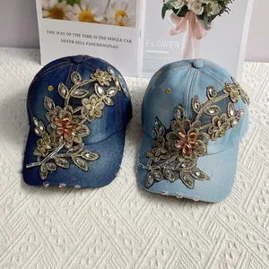 Detailaufnahme von Denim-Baseballkappen mit goldener Blumenstickerei und glänzenden Strasssteinen
