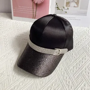 Close-up of black satin baseball cap featuring glitter brim and rhinestone buckle strap