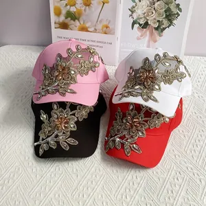Detail der Goldfaden-Blumenstickerei und Strasssteine auf einer Denim-Baseballkappe