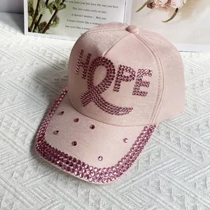 Detail of pink baseball cap with HOPE rhinestone letters and ribbon on a floral magazine