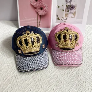 Detail of glittery crown sequin embroidery and pearl trim on denim baseball caps
