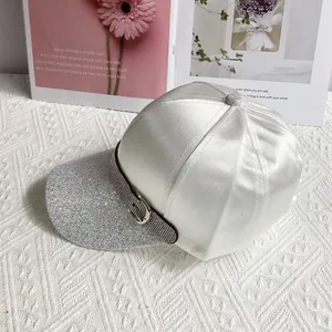 Detail of white satin baseball cap with rhinestone buckle and silver glitter brim