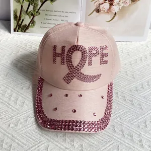 Detailed close-up of pink baseball cap with HOPE rhinestone letters and ribbon motif